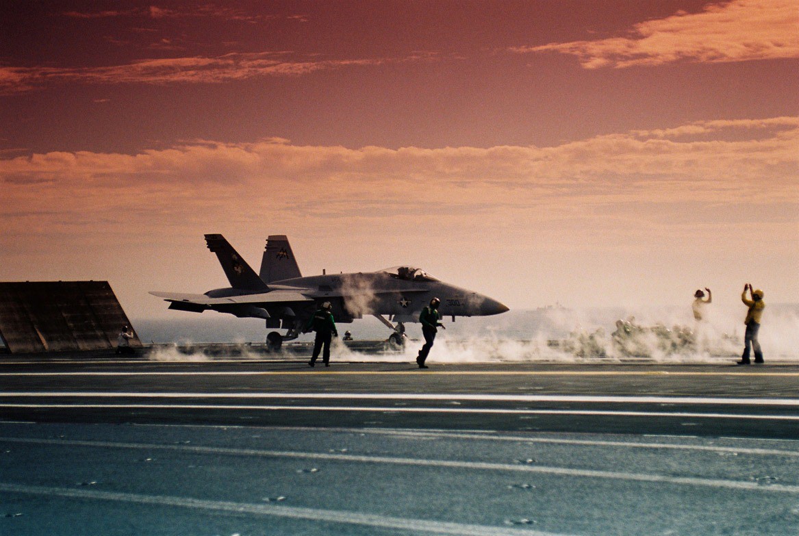 A fighter jet prepares to take off from the deck of an aircraft carrier