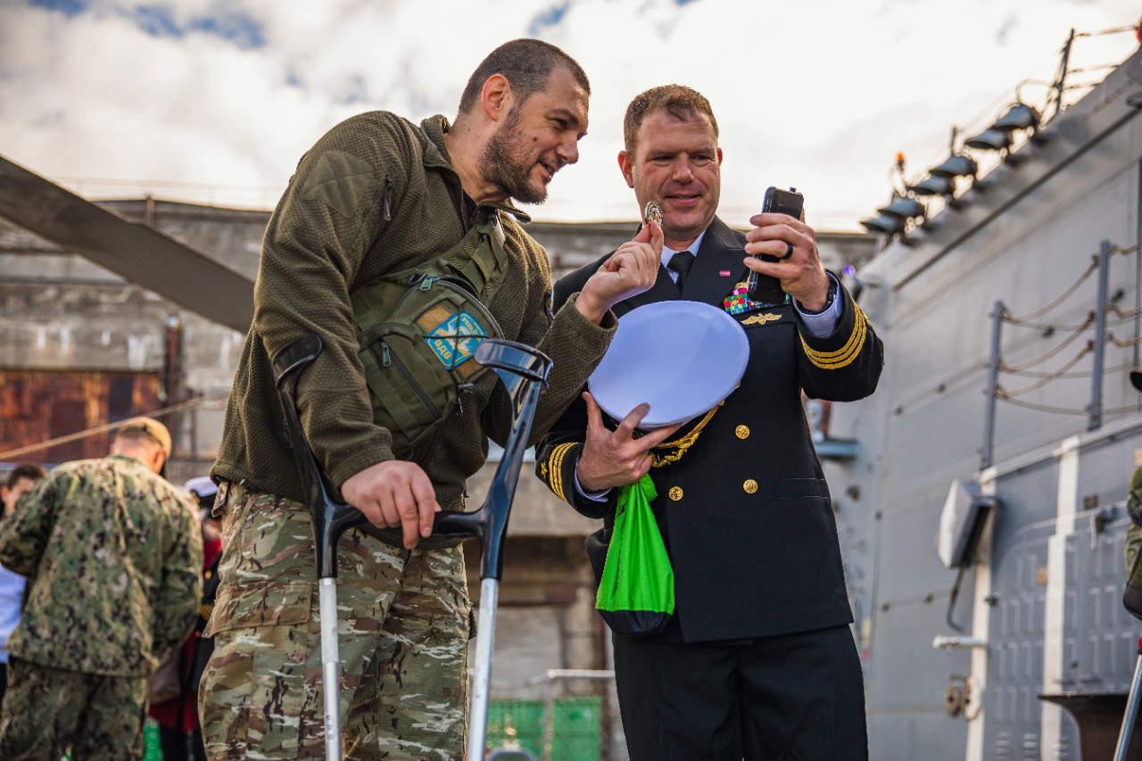 Cmdr. Aaron Arky, right, commanding officer of the Arleigh Burke-class guided-missile destroyer USS Paul Ignatius (DDG 117), speaks with a Ukrainian soldier