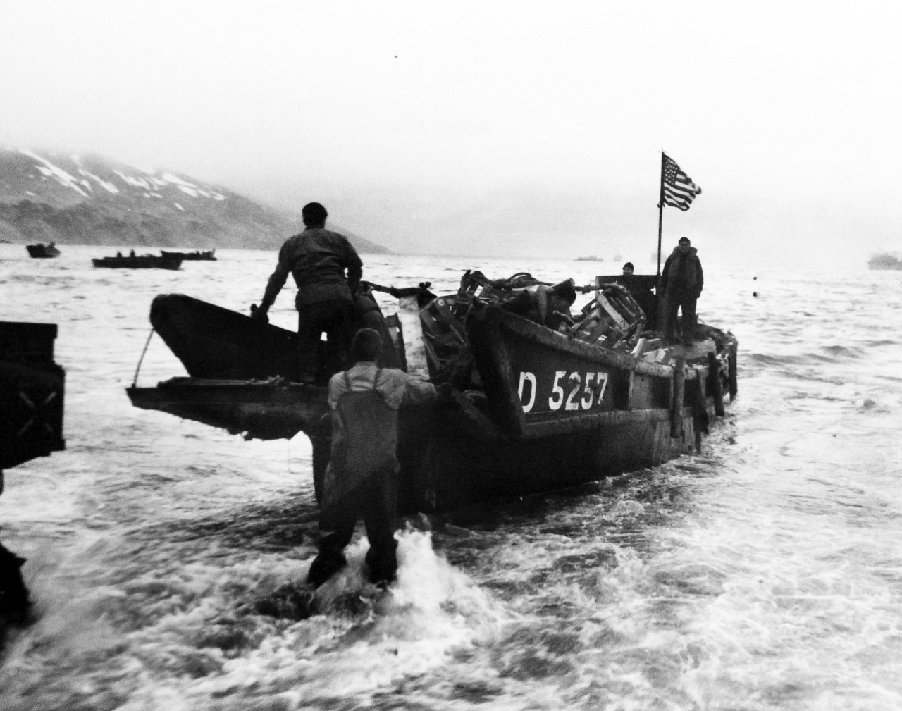 LC-Lot-803-30:  Aleutian Islands Campaign, June 1942 - August 1943.   Allied Landing on Attu Island, May 11 1943.   Old Glory Waves From a Japanese Landing Boat.  Americans bring ashore a captured Japanese landing boat at Attu.  The American flag is prominently displayed.  The scene was the beach at Massacre Bay. U.S. Navy photograph, released May 27, 1943.   Photographed through Mylar sleeve.  Courtesy of the Library of Congress.  (2015/11/06).