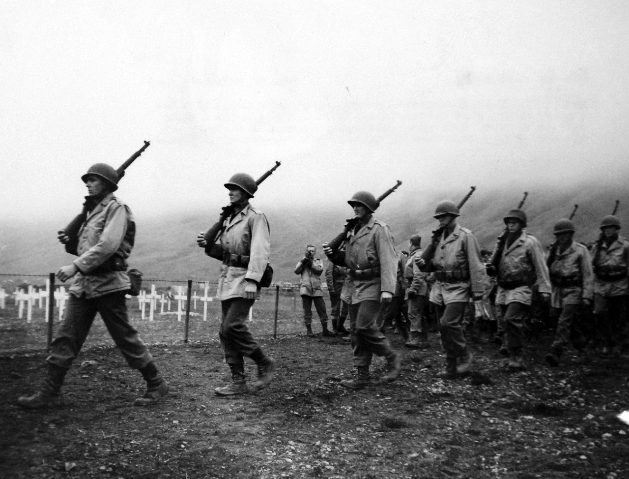 LC-Lot-803-31:  Aleutian Islands Campaign, June 1942 - August 1943.   Allied Landing on Attu Island, May 11 1943. Against the Crosses Row on Row – Marching past the white crosses of an Attu cemetery on the bleak Aleutian Island, soldiers prepare to fire a volley shot in honor of their fallen comrades – in memoriam.  In the background, the rolling fog presses downward, emphasizing the solemnity of the occasion.   U.S. Navy photograph, released September 7, 1943.   Photographed through Mylar sleeve.  Courtesy of the Library of Congress.   (2015/11/06).