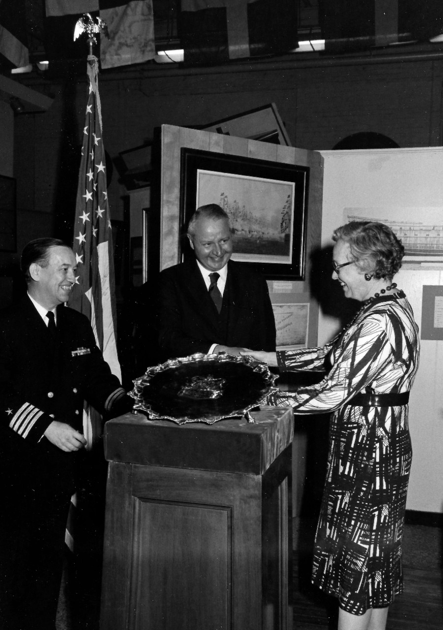 NMUSN-138: Presentation of HMS Intrepid Silver Tray, April 1975. Shown: Mrs. Edward R. Murrow gives holds the tray while Navy Memorial Museum Director, Captain Roger Pineau, far left, and Secretary of the Navy J. William Middendorf look on at the...
