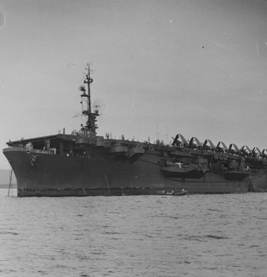 USS Palau (CVE-122) at anchor, with F4U Corsair fighters parked on her flight deck.