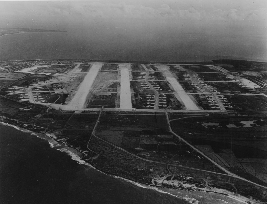 Black-and-white aerial photograph of Tinian, showing rows and rows of parked aircraft, which the caption identifies as B-29s belonging to the U.S. Army Air Force.