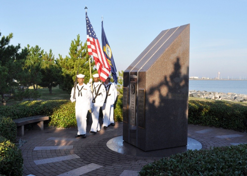 Members of a Navy honor guard from the guided-missile destroyer USS Cole practice rendering colors before a memorial service at the USS Cole Memorial at Naval Station Norfolk.