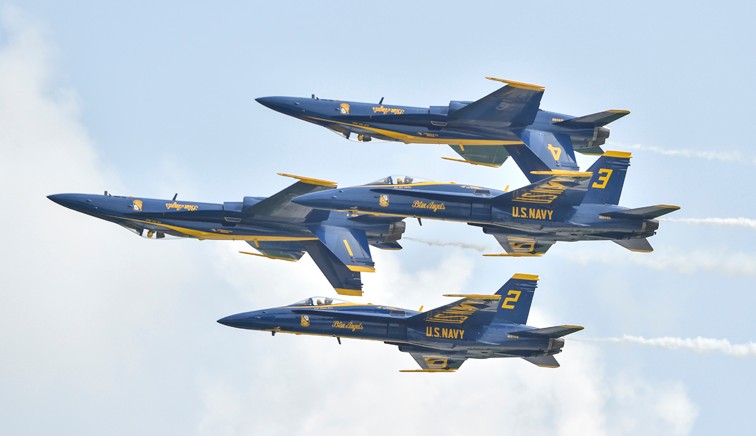 Four Blue Angels FA-18 Hornets in diamond formation with the number one and number four jets flying inverted