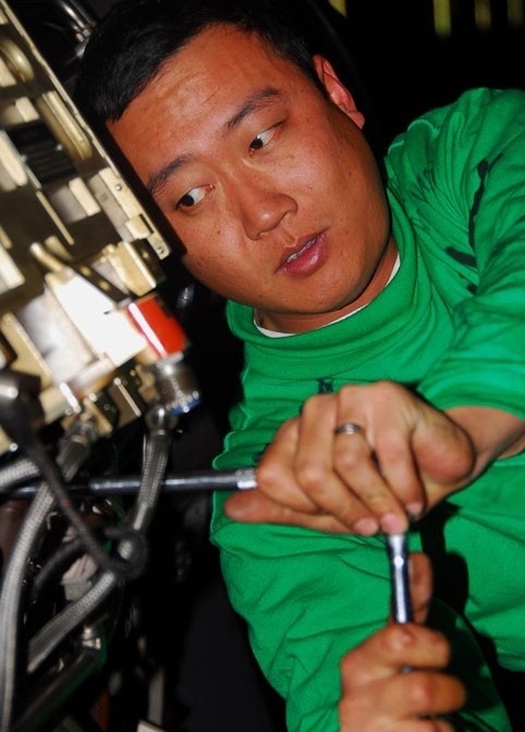 Aviation machinist's mate performs aircraft engine maintenance on a carrier.