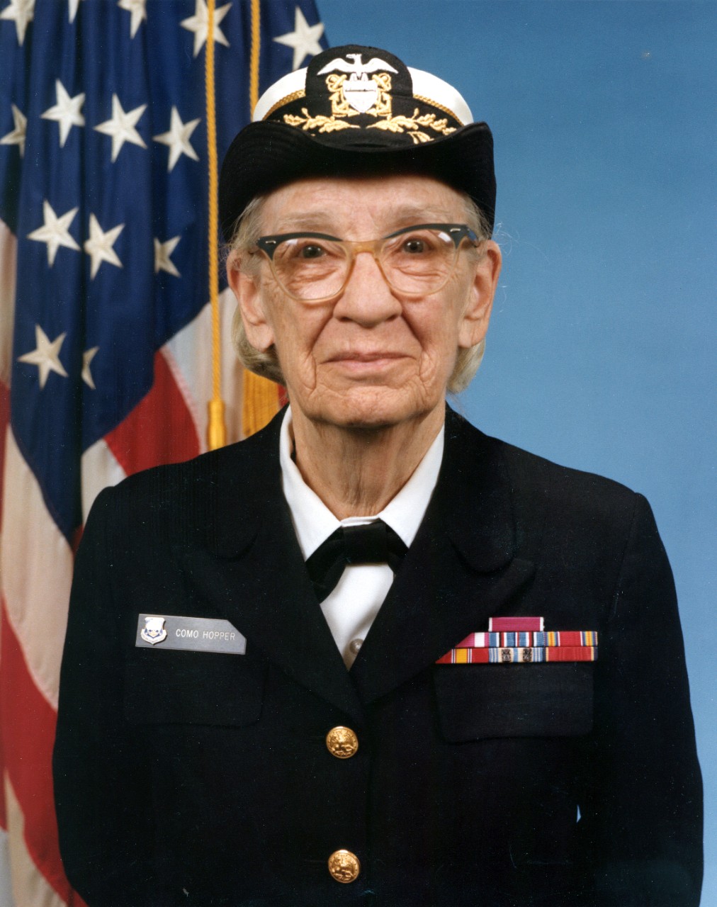 Formal portrait of an older woman in uniform and cover with American flag in background.