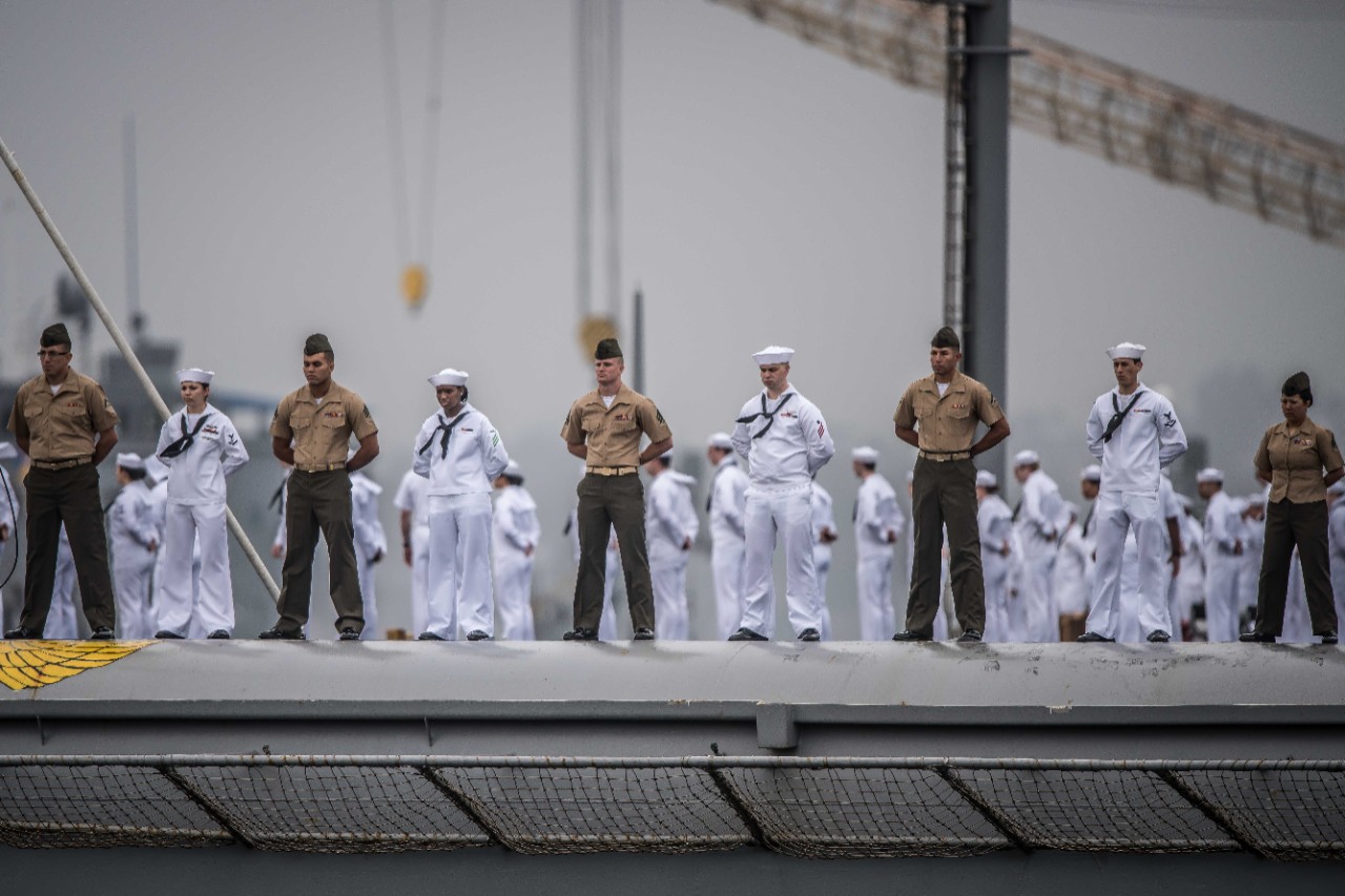 Sailors and Marines aboard the aircraft carrier USS Nimitz (CVN-68) man the rails and give passing honors to the USS Midway Museum.