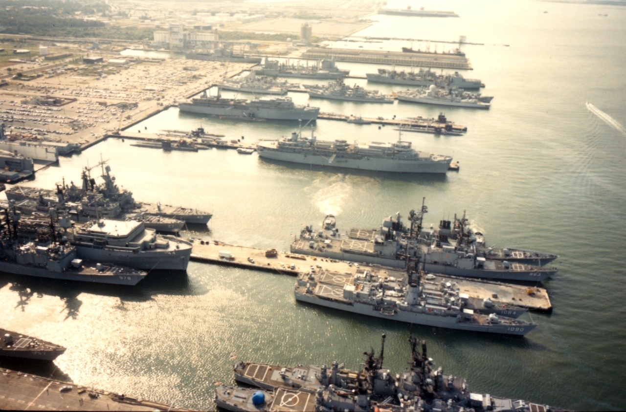 Naval Station, Norfolk, VA - an aerial view of the destroyer and submarine piers (Nos. 22 and 23) with various ships at anchor, including destroyers, frigates, cruisers, destroyers and submarine tenders and submarines. October 1984.