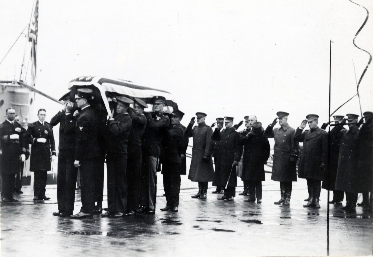 A detail of Marines and sailors lift the body of the unknown soldier as the funeral party disembarks USS Olympia (CL-15) at Washington, DC after its trip from Le Harve, France. Original image is from the collections of the Marine Corps, #521811.