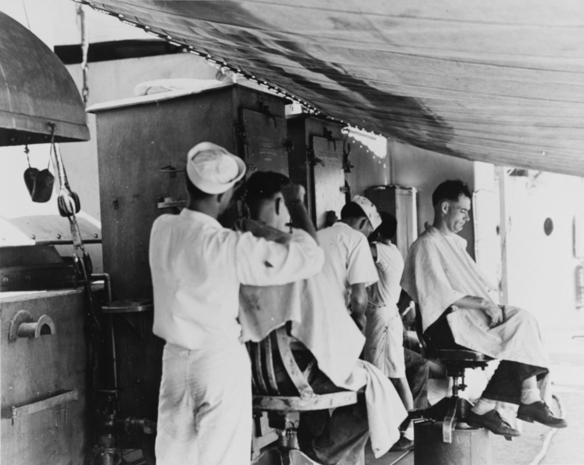USS Marblehead (CL-12), view taken aboard ship in February 1942. Showing makeshift barbershop rigged up under an awning amidships. Shop belowdecks had been damaged during the air attack which heavily damaged the ship on 4 February 1942 in the Flo...