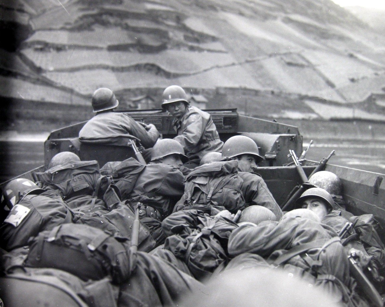 Crouching low for concealment and protection in a DUKW amphibious vehicle, men of the 89th Division, U.S. Third Army, cross the Rhine River at Oberwesel, Germany.