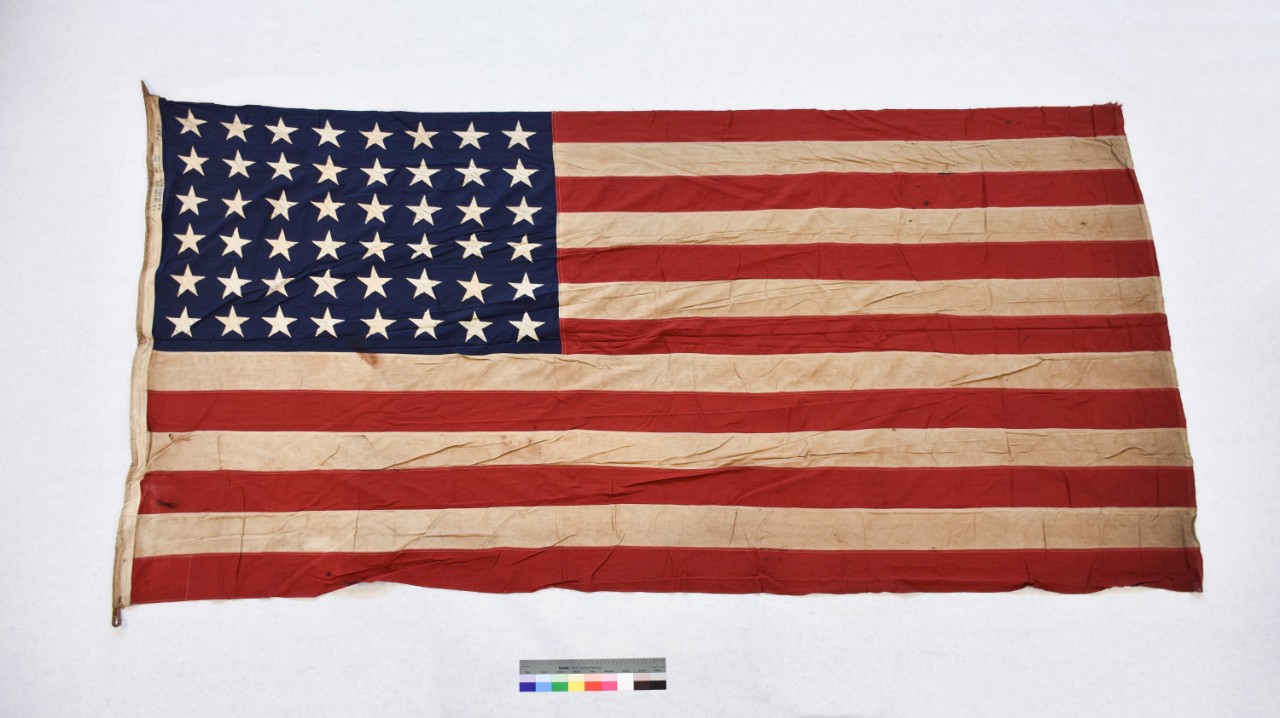 One forty-eight-star national ensign from the escort aircraftcarrier USS Thetis Bay (CVE-90). The flag is cotton, of sewn construction and rectangularin shape. Seven alternating horizontal stripes of red and white are joined to ablue canton in th...