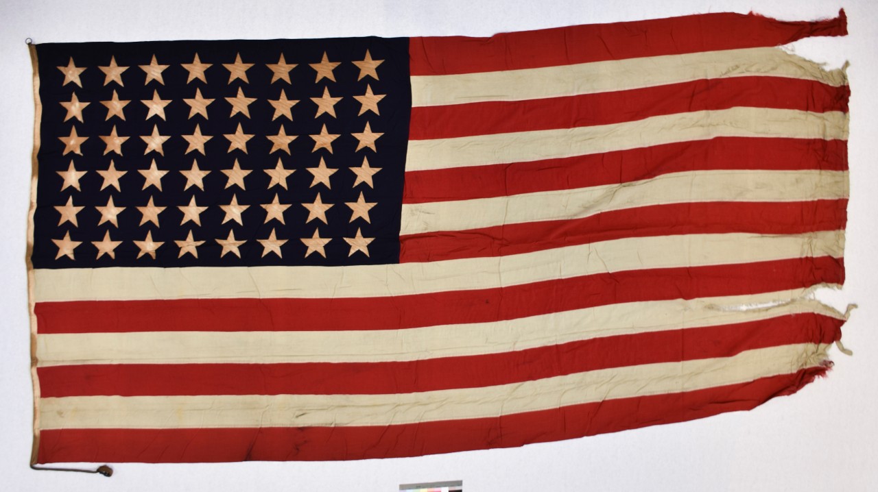 One forty-eight-star national ensign from the light aircraft carrier USS Cowpens (CVL-25). The flag is cotton, of sewn construction and rectangular in shape. Seven alternating horizontal stripes of red and white are joined to a blue canton in the...