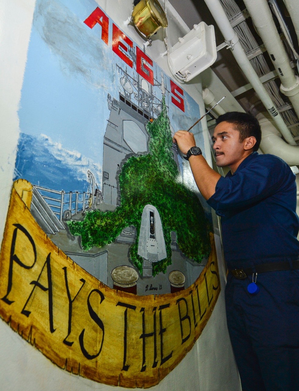 Fire Controlman 3rd Class Brandho Linao paints artwork on a bulkhead aboard the guided-missile cruiser USS Monterey (CG 61).