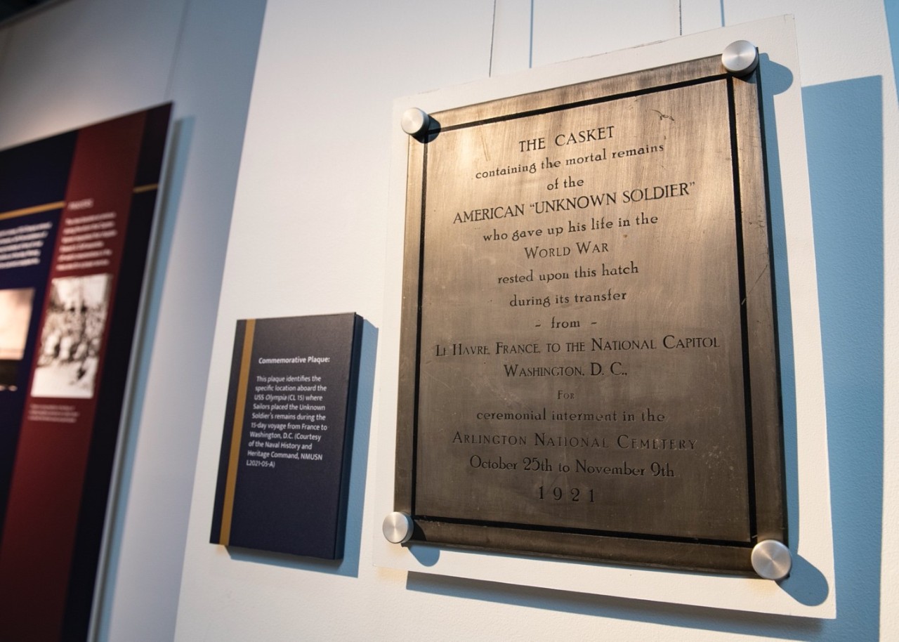 A commemorative plaque, part of the exhibit of the cruiser USS Olympia at the National Museum of the U.S. Navy (NMUSN), hangs on display during a symposium held to commemorate the 100th anniversary of the arrival of the Unknown Soldier to U.S. so...