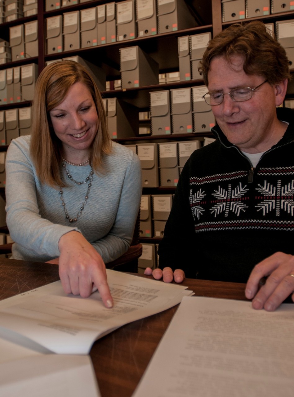 Laura Waayers, an archivist at Naval History and Heritage Command (NHHC), and Dale "Joe" Gordon, the lead reference archivist at NHHC, read through a command operations report (COR).
