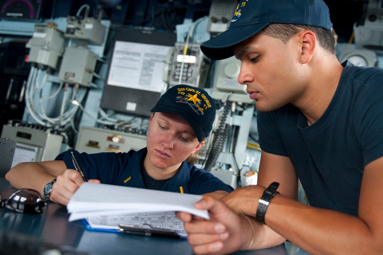 U.S. Navy Quartermaster 3rd Class Richard Carre, right, instructs Ensign Alexandra Dauernheim on proper procedures for using a deck log on the bridge of the guided missile cruiser USS Cape St. George (CG 71) in the Arabian Sea, April 19, 2012. Ca...