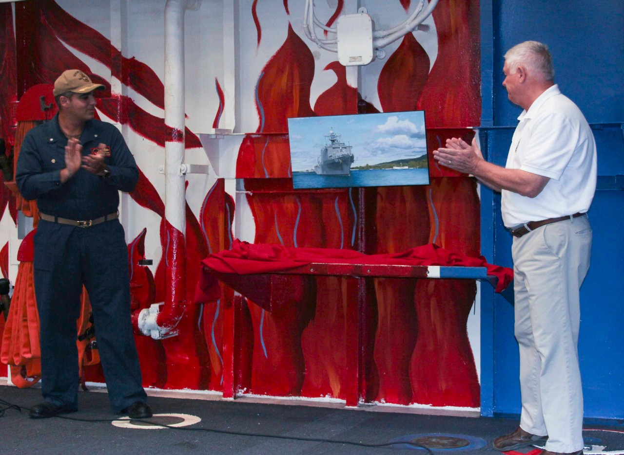 Commanding Officer, CDR Sameer Khanna, and NHHC’s Combat Artist Douglas Rowe unveil and present a reproduction print of Rowe’s painting for the Navy’s art collection titled, “USS PEARL HARBOR".