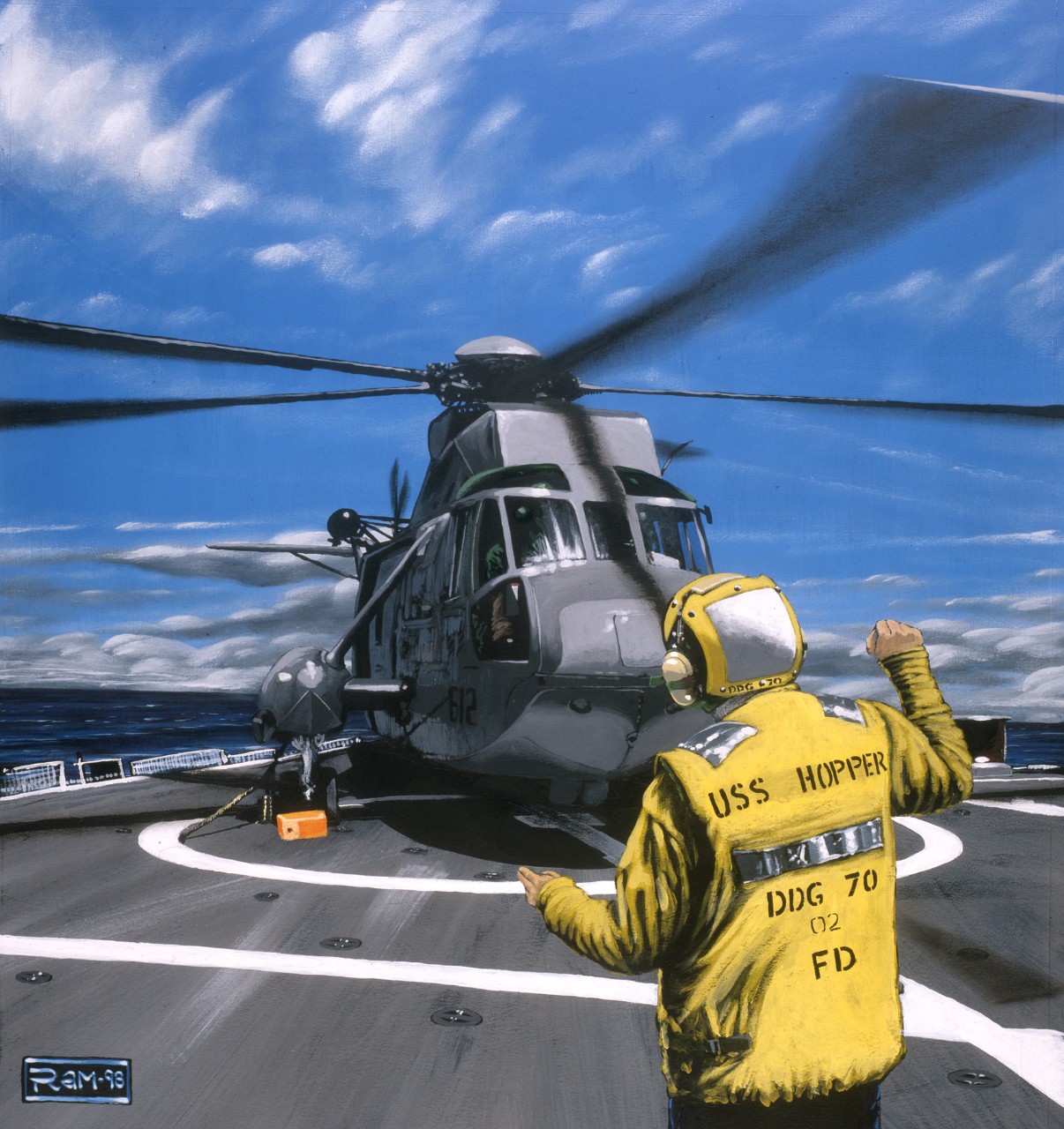 A crewman directs a helicopter on the landing pad
