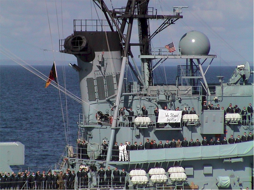 Sailors aboard German destroyer Lutjens manning the rails and displaying a homemade banner saying "We stand by you." Photo taken from USS WInston S. Churchill (DDG-81).