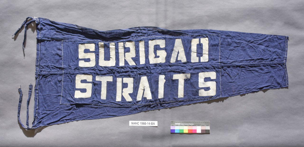 Blue Pennant with white letters Surigao Straits. Streamers at either end of the hoist