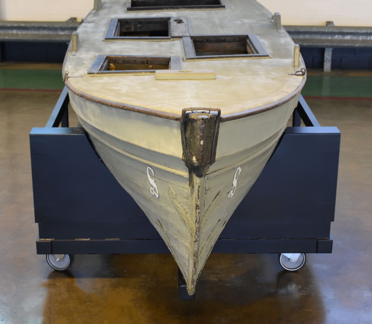 Bow view of small boat. White S painted on both sides of bow beam.