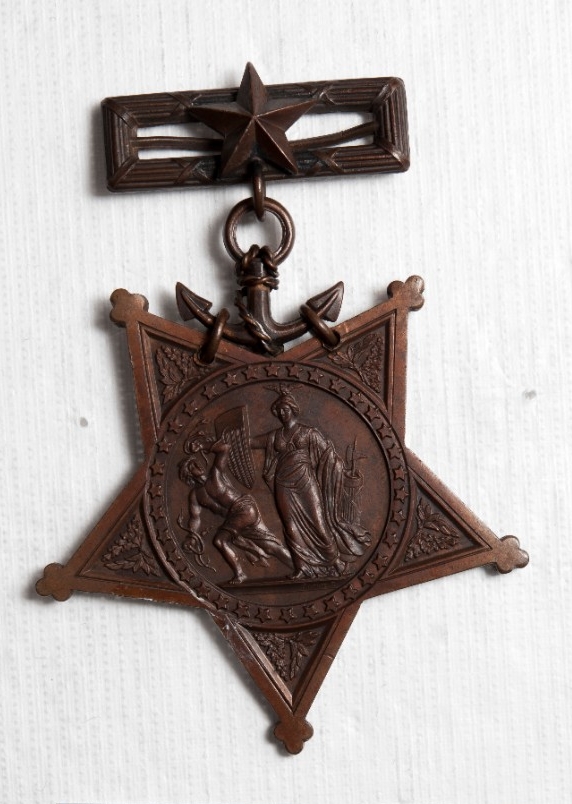 5 pointed bronze star mounted with ribbon bar and foul anchor suspension ring. Minerva repelling evil in center of star. 