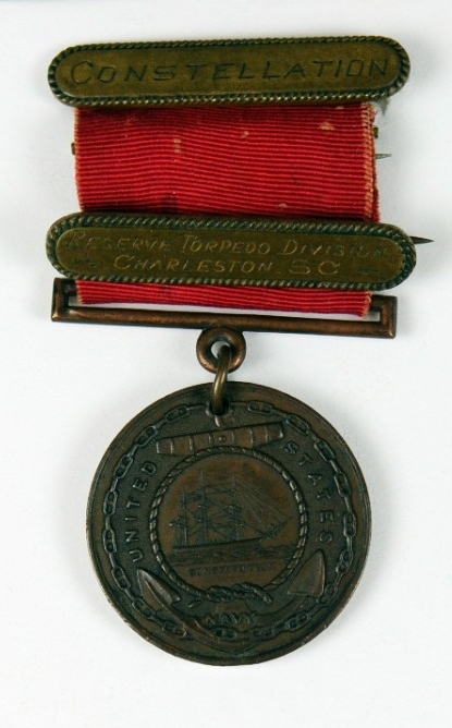 Good Conduct planchet with red ribbon and two devices attached to ribbon, one with pin and clasp brooch