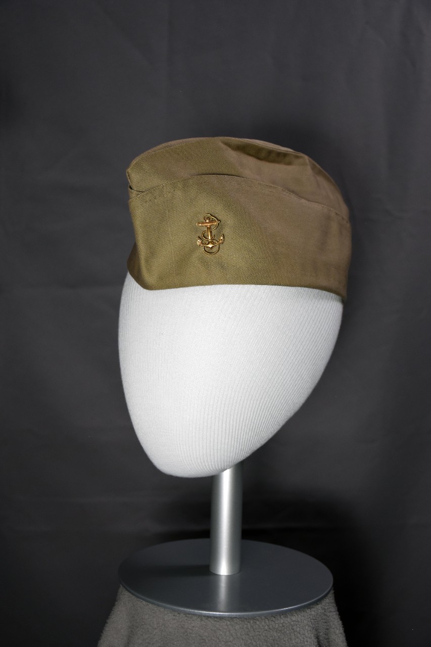Khaki garrison cap with brass anchor on the proper left side.