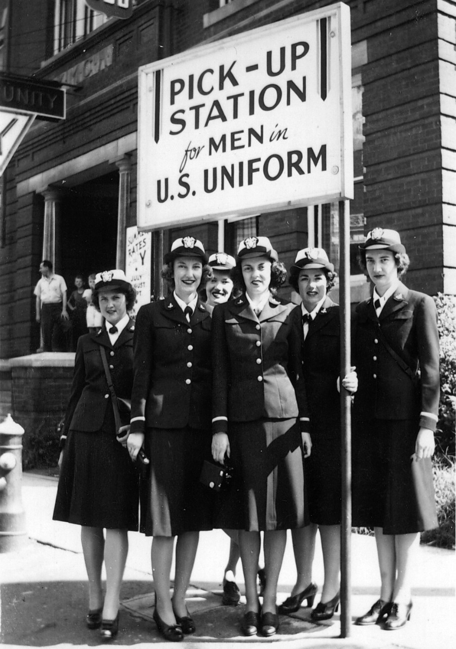 One black and white copy print showing WAVES in front of a sign reading “Pick-Up Station for Men in U.S. Uniform,” donated by Lindy Ader in 2008 and transferred from Curator Branch. Donor’s mother, Cicely Frances Peeples, is at far right in photo. Photo possibly taken in Washington, D.C.
