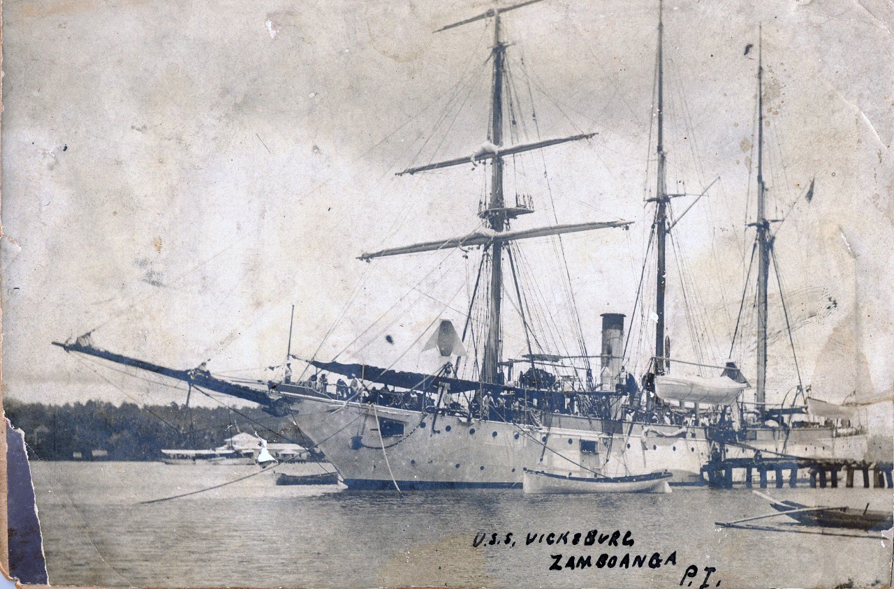 Collection of 6 photos related to USS Vicksburg (PG-11), including in China & the Philippines, circa early 1900s. Specific images include several army officers aboard USS Vicksburg following their capture of Philippine president, Emilio Aguinaldo, at Palanan, Isabela in March 1901; coaling while docked in China; Chinese villagers selling goods in Shanghai, China, and the ship docked in Zamboanga, Philippines. 