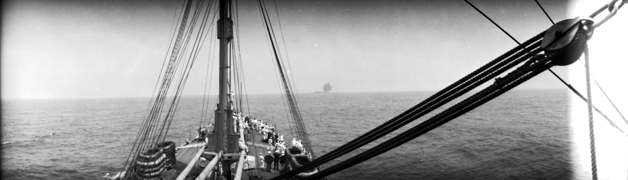 Sailors on board USS Henderson (AP-1) watch as an explosion rocks Ex-SMS Ostfriesland on the horizon, during the 1921 Army-Navy bombing exercises off the Virginia capes.  