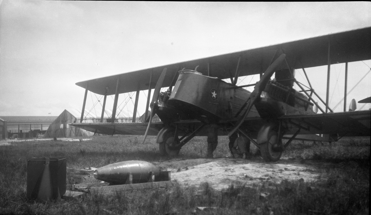 Ground crews inspecting the fuselage of a Martin MB-2 in order to mount ordinance on to the aircraft, circa 1921, likely in support of aerial bombing exercises in conjunction with the Navy.