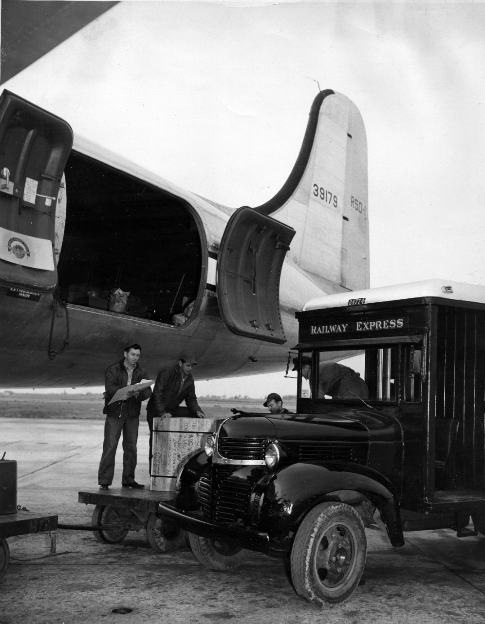 Loading cargo on to a Naval Air Transport Service (NATS) aircraft from a Railway Express vehicle. The crate being loaded is from Honolulu, HI to Naval Air Station Patuxent River, MD, circa 1944. 