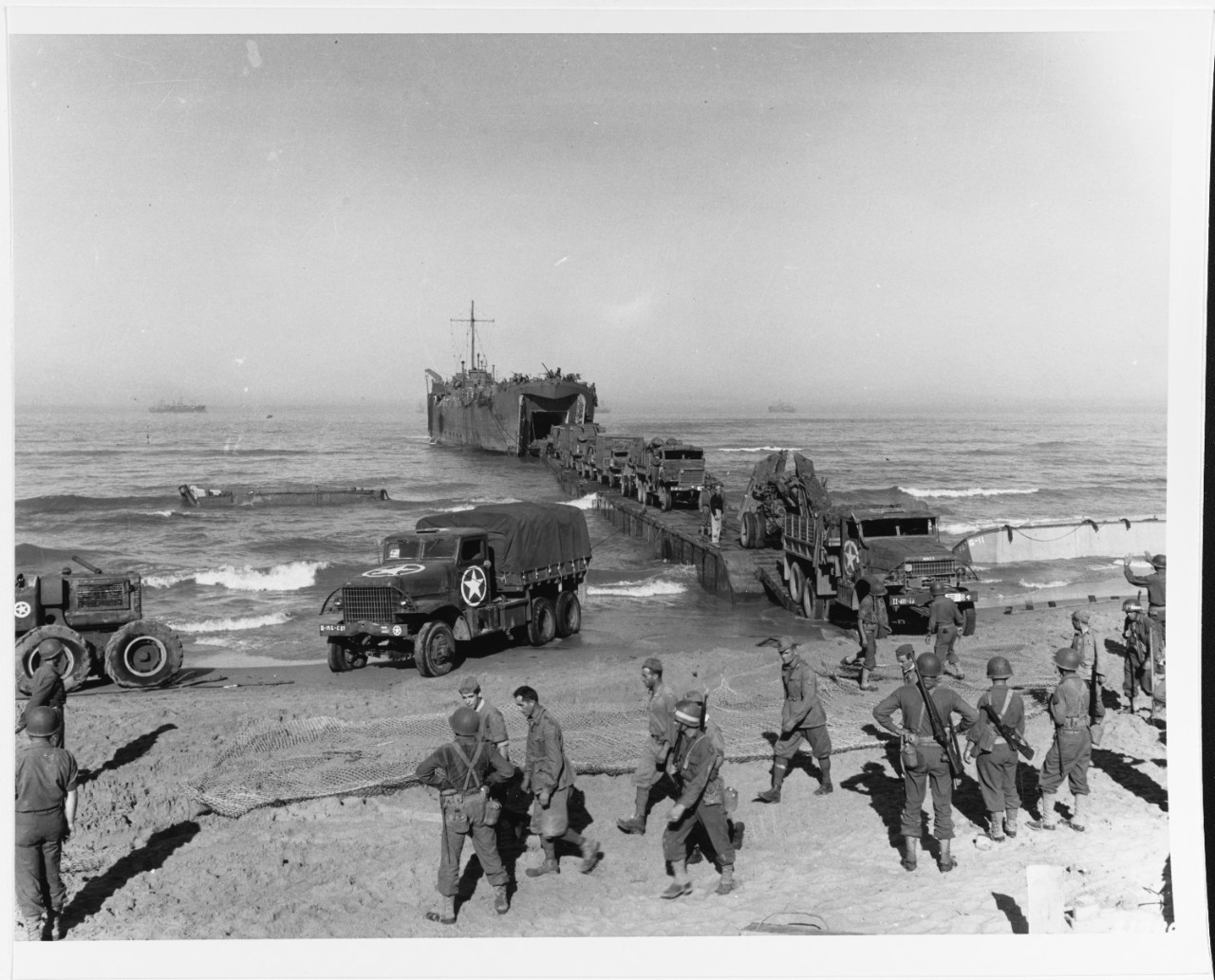 Sicily Invasion, July 1943. USS LST-336 unloads trucks over a pontoon causeway, near Gela