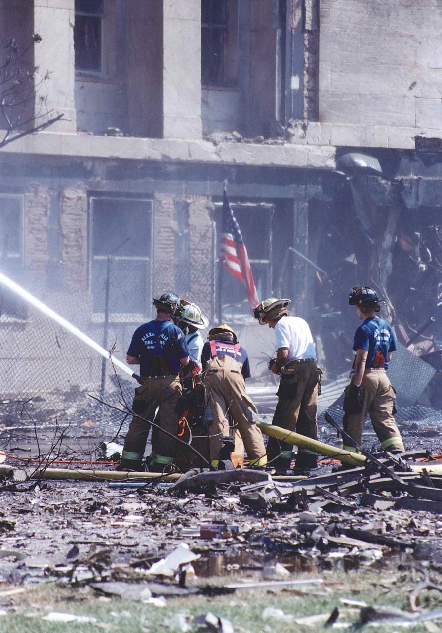 Fire crews work while standing amidst piles of debris, 11 September 2001
