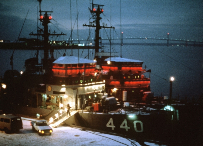 Exploit (left) and Affray are brightly illuminated to celebrate the season while moored at Newport, 1 December 1982. Snow covers the pier and the Mount Hope Bridge rises in the background. (JO2 Lance Johnson, Department of Defense Photograph 330-CFD-DN-ST-83-11429, Record Group 330 Records of the Office of the Secretary of Defense, 1921–2008, National Archives and Records Administration)