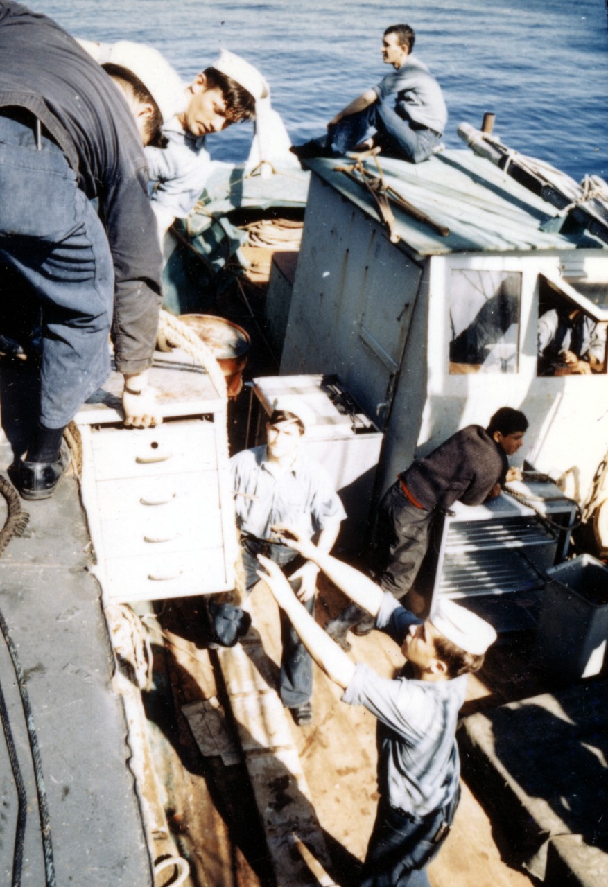 BM3 S. M. Vukovich passes down salvaged equipment down to FN R. J. Dumont and MM3 P. S. Glowacki who are on the deck of a Greek vessel alongside the grounded Bache, 9 February 1968, three days after she had grounded and suffered irreparable damag...