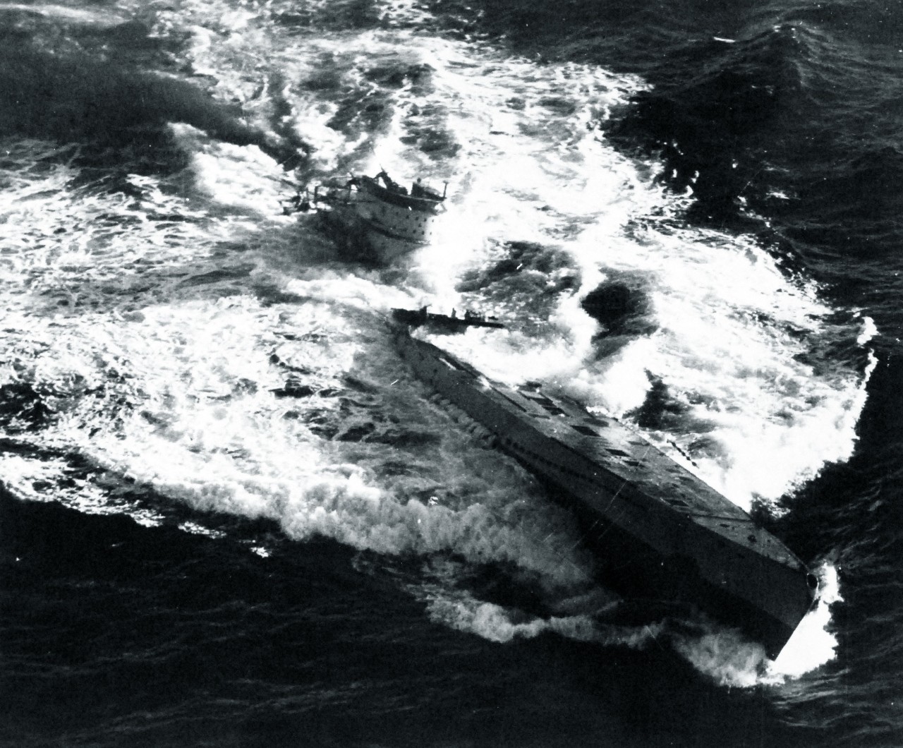 U-185 sinks, 24 August 1943. Note that the bomb that hits forward all but blasts her 4.1-inch deck gun over the side, that the U-boat lists slightly to port, and that she has lost trim by the stern. (Unattributed U.S. Navy Photograph 80-G-77196, ...