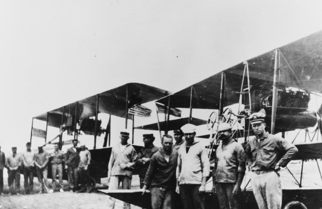 Some of the men at the aviation camp at Vera Cruz take a few moments for pictures; Lt. (j.g.) Patrick N. L. Bellinger stands defiantly (right), and the Stars and Stripes identify aircraft. The Curtiss AH pusher behind Bellinger may be the first U...