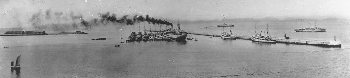 Panoramic photograph of Chefoo harbor during the 1930s. Black Hawk lies moored in the center, with the destroyers of Destroyer Division (DesDiv) 14 alongside. Two U.S. Navy minesweepers are by the breakwater and a gunboat is anchored off shore, a...