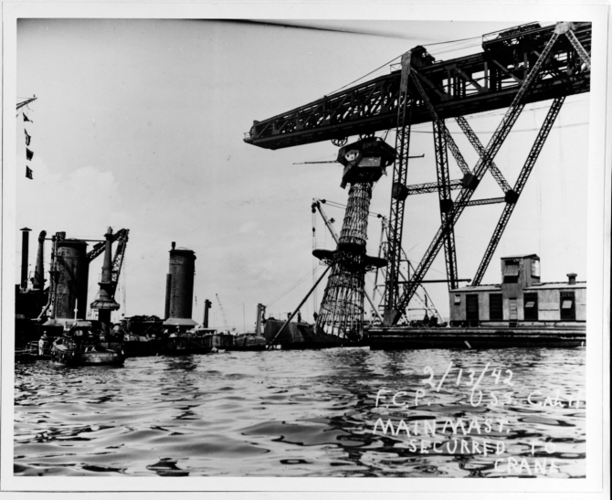 A floating crane removes the ship’s battered “basket” mainmast during her salvaging, 13 February 1942. (Courtesy of Vice Adm. Homer N. Wallin, 1975 (Naval History and Heritage Command Photograph NH 55038)