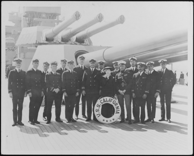 Officers of the ship’s company pose with Dorothy Devore, a silent film star and comedian on board the ship at San Pedro, Calif., 1925. Devore (22 June 1899–10 September 1976) was cast in 36 films during a career spanning two decades. Lt. Abraham DeSomer stands third from the right. Note the caps in the barrels of the triple 14-inch guns, and the overall cleanliness of the ship, the deck of which has likely been holystoned for the event. (Collection of Lt. Cmdr. Abraham DeSomer, donated by Lt. Col. Russell DeSomer, USAFR, 1975) (Naval History and Heritage Command Photograph NH 103839)