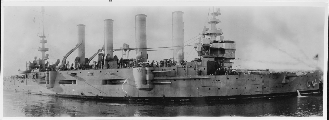 A photograph of Charleston, circa 1917. The panoramic view emphasizes the ship’s diverse armament including some of her 6-inch guns in their “box battery”, mounted on the gun deck within the upper casemate, with separating splinter bulkheads, the...