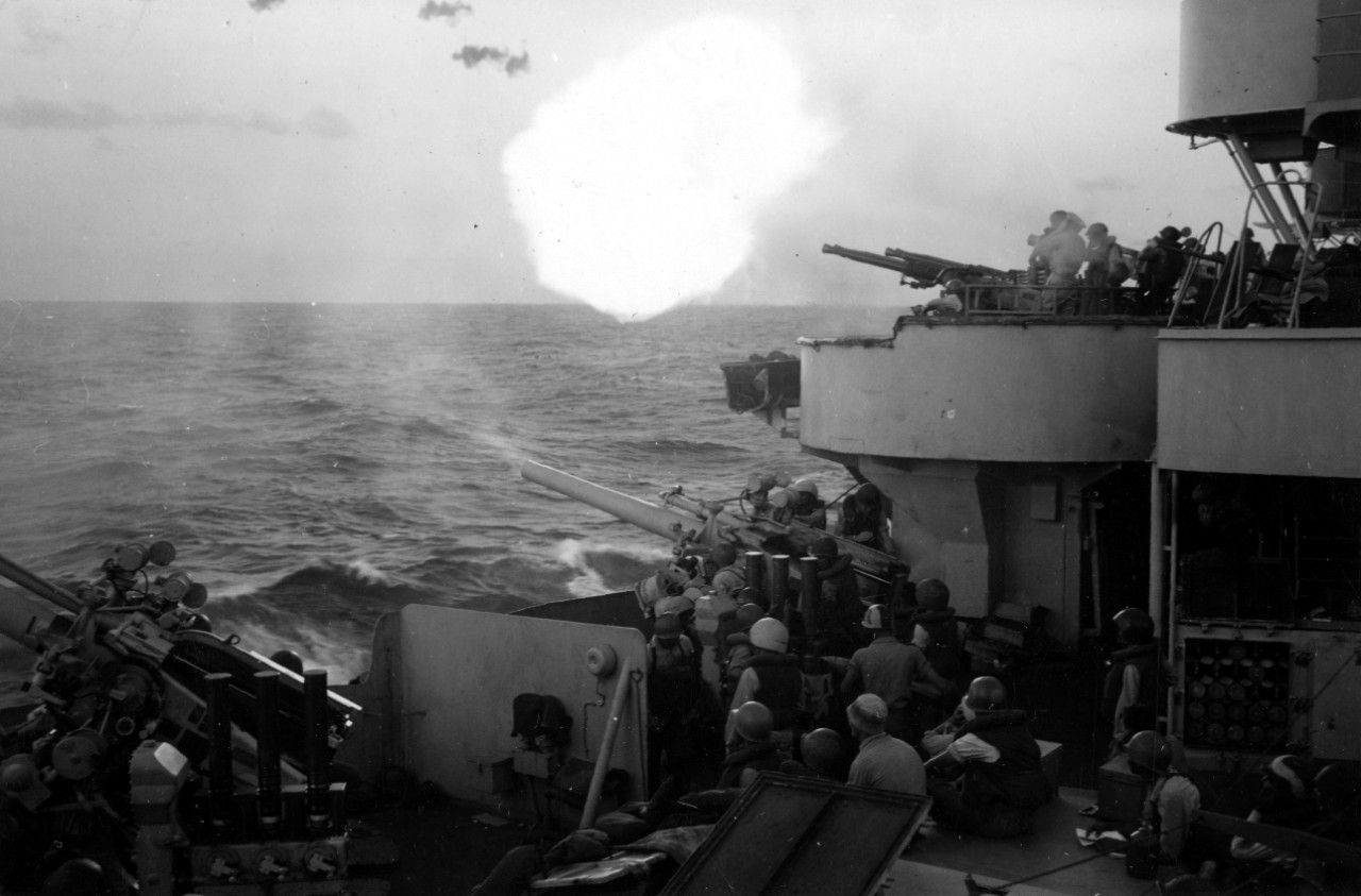 Off Iwo Jima, one of Chester’s 5-inch guns on her flight deck opens fire while the crew of a 40 millimeter mount and a 5-incher on the deck below look on, 19 February 1945. (U.S. Navy Photograph 80-G-305119, National Archives and Records Administ...