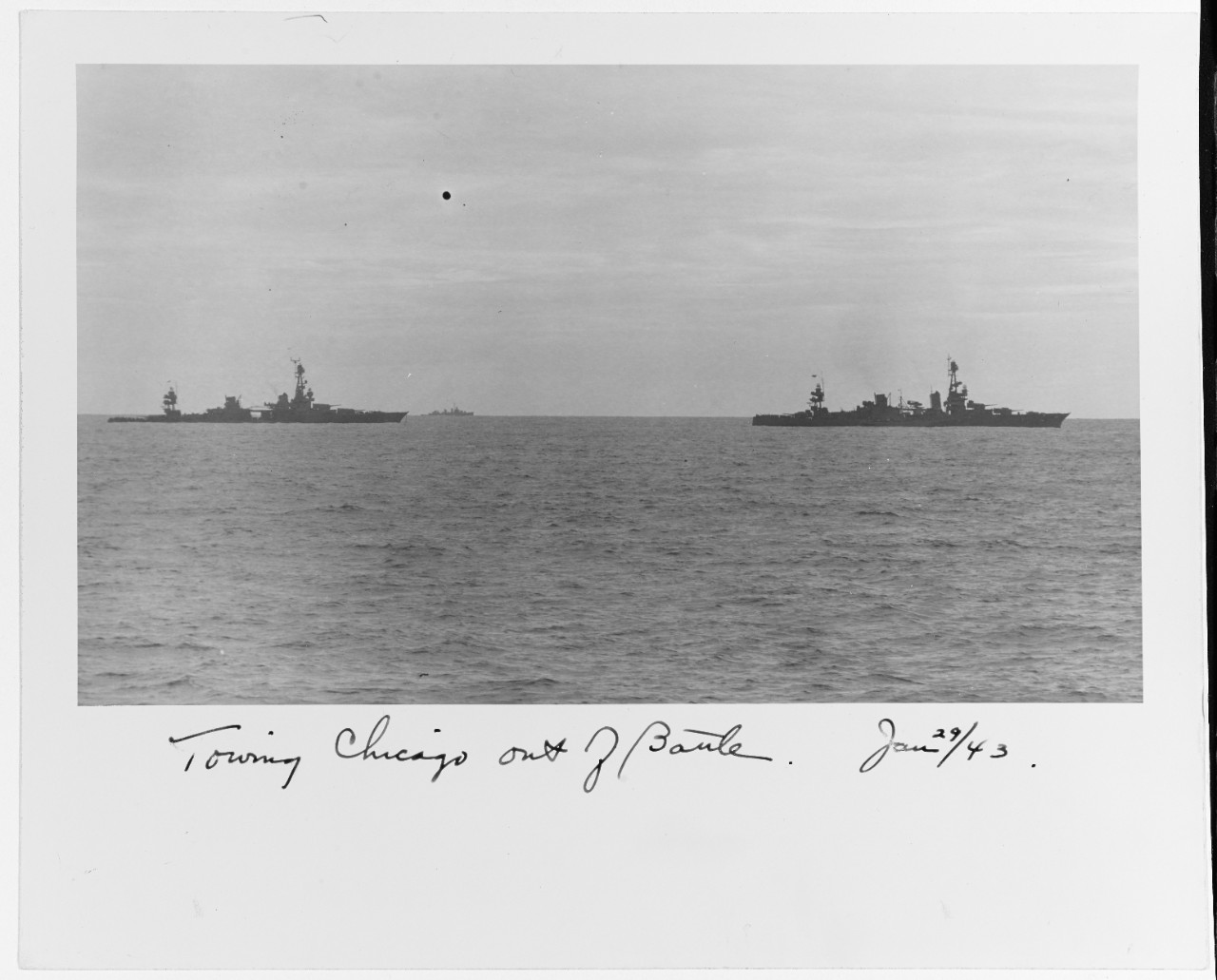 Chicago (left) slowly emerges from the battle under tow of Louisville on the morning of 30 January 1943. A tug, most likely Navajo (AT-64), steams alongside Louisville. (Collection of Vice Adm. Robert C. Giffen, Naval History and Heritage Command...