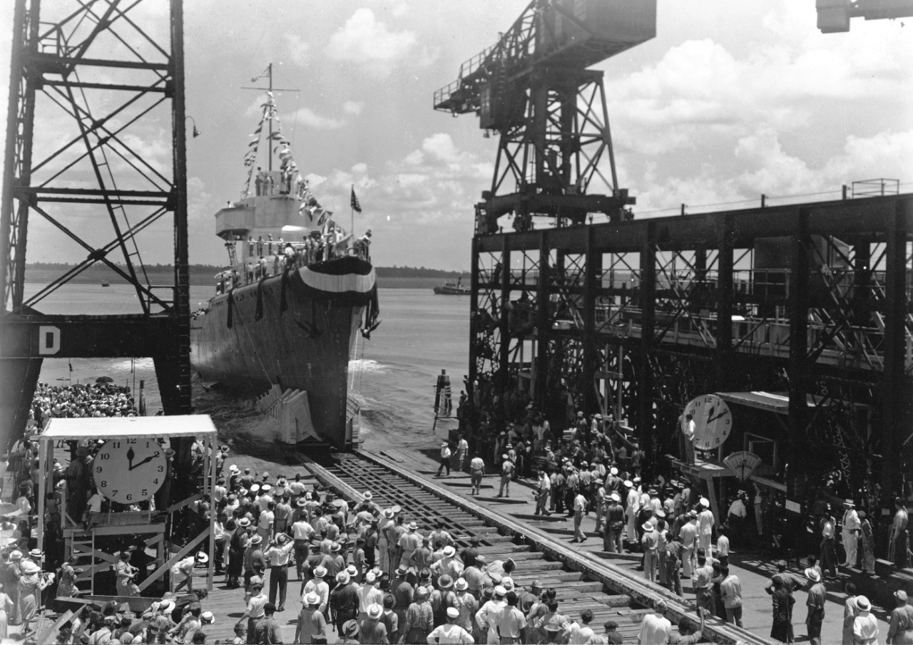 On a bright, sunny day, Corry slides down the building ways at Charleston Navy Yard, 28 July 1941 to an enthusiastic send-off. Note children scrambling on the shaded platform at left, and the women picking their way across obstructions at lower l...
