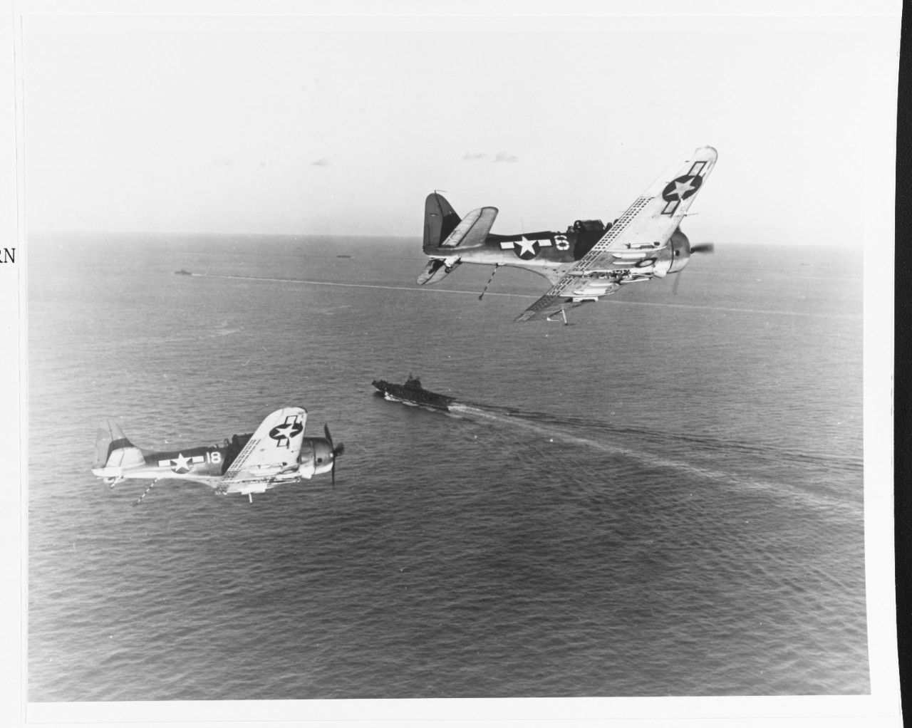 A pair of SBD-5s of VB-20 lower their tail hooks and turn into the landing pattern while returning to the ship after bombing the Japanese in Palau, March 1944. (U.S. Navy Photograph 80-G-251061, National Archives and Records Administration, Still...
