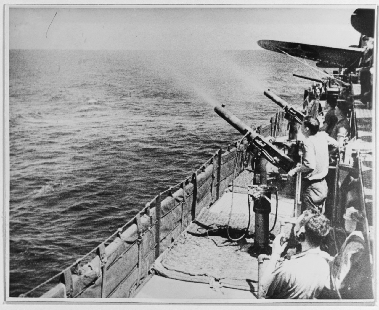 Crewmen practice firing .50 caliber machine guns, early 1942. The wing of a Dauntless is visible (right). (Naval History and Heritage Command Photograph NH 50935)
